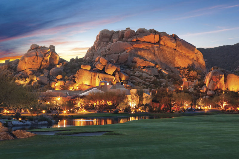 Golf course with rock formations and illuminated buildings at dusk